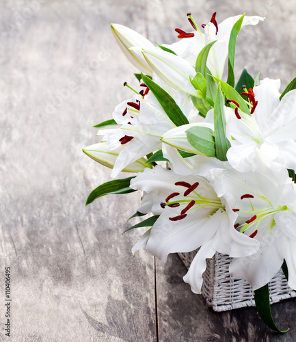 Fototapeta Naklejka Na Ścianę i Meble -  White  basket with white lily flowers bouquet on rustic wooden t