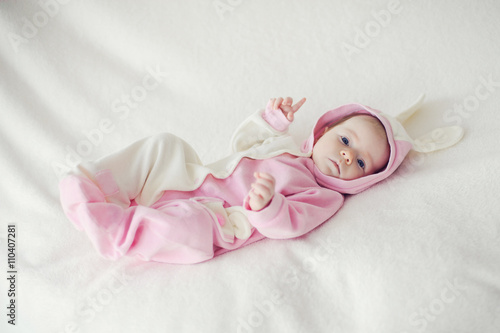 Baby lying on white blanket in Bunny costume.