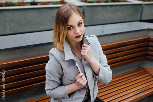 Young woman sitting on the bench in front of buindings photo