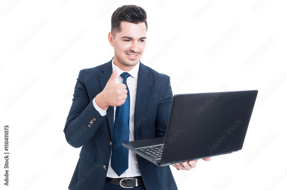 Joyful young salesman holding laptop and thumb up Joyful young salesman holding laptop and thumb up