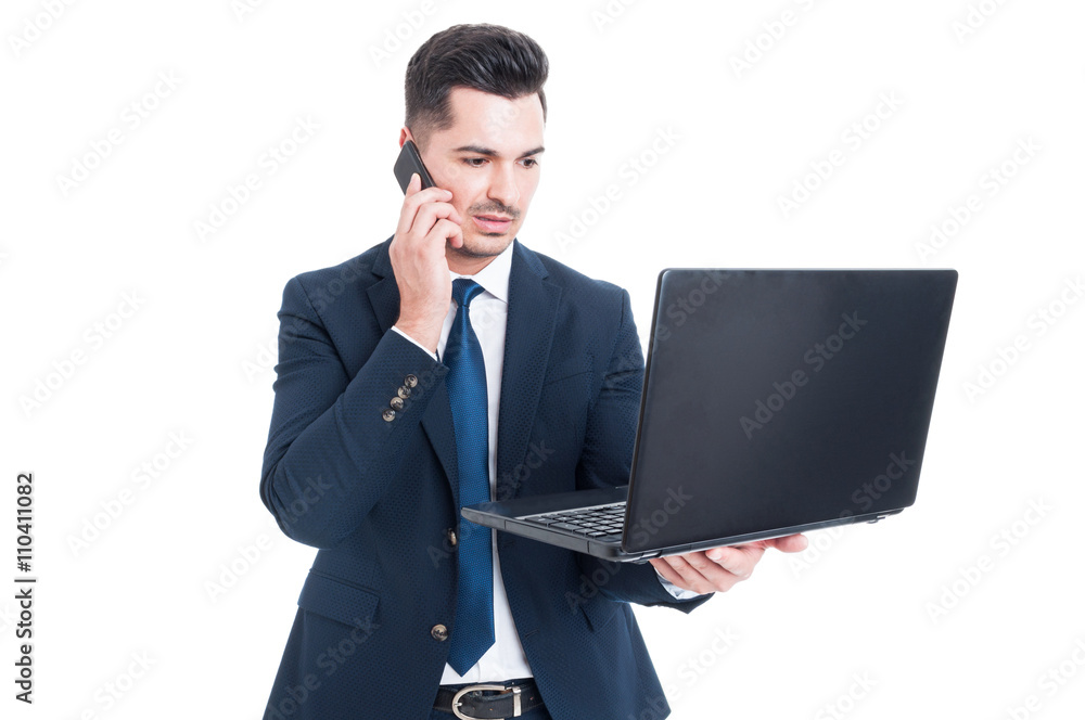 Handsome businessman talking on smartphone and working on laptop Handsome businessman talking on smartphone and working on laptop