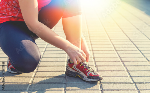 Sport woman tying running shoes during training in the morning