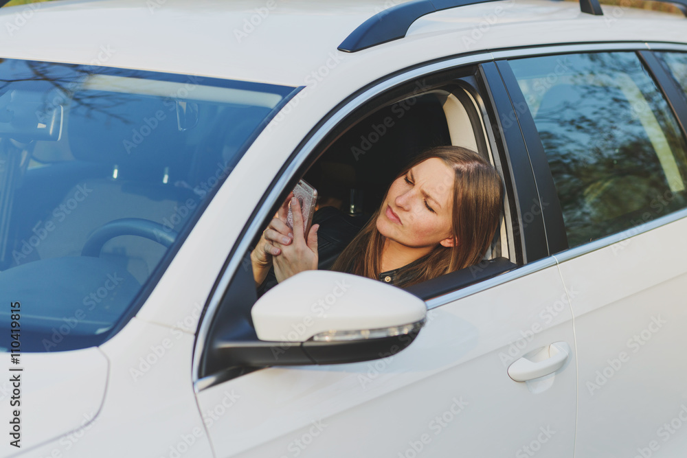 young woman using mobile phone while driving a car