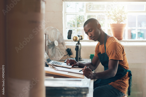 фотографія African small business owner working seriously at his studio desktop