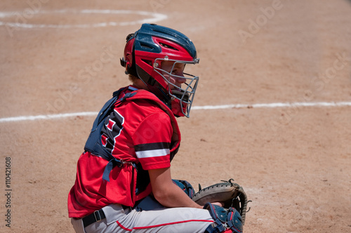 Teen baseball catcher behind home plate.