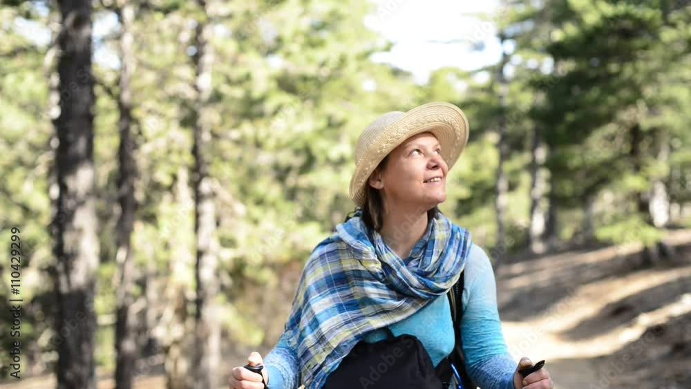 Woman hiker in a straw hat, standing on a trail in the forest, happily looks around, smiling and laughing. Sunny day in Cyprus. Woman hiker in a straw hat, standing on a trail in the forest, happily looks around, smiling and laughing. Sunny day in Cyprus.