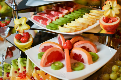 Plates with different type of fruits: strawberry, pineapple, orange, kiwi