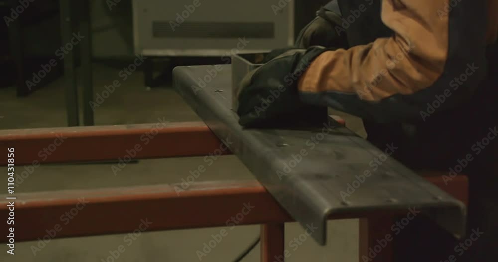 A piece of metal being assembled by the worker. The square metal on top of a long metal bar A piece of metal being assembled by the worker. The square metal on top of a long metal bar