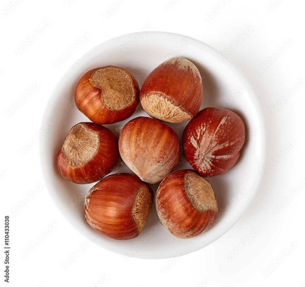 Fototapeta premium Bowl of hazelnuts isolated on white, from above