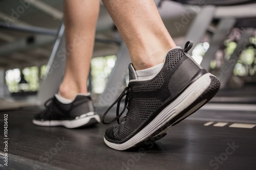 Man's feet while walking on thread mill