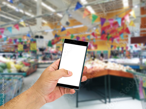 Man hand holding smart phone over blurred shopping center or super market background.
