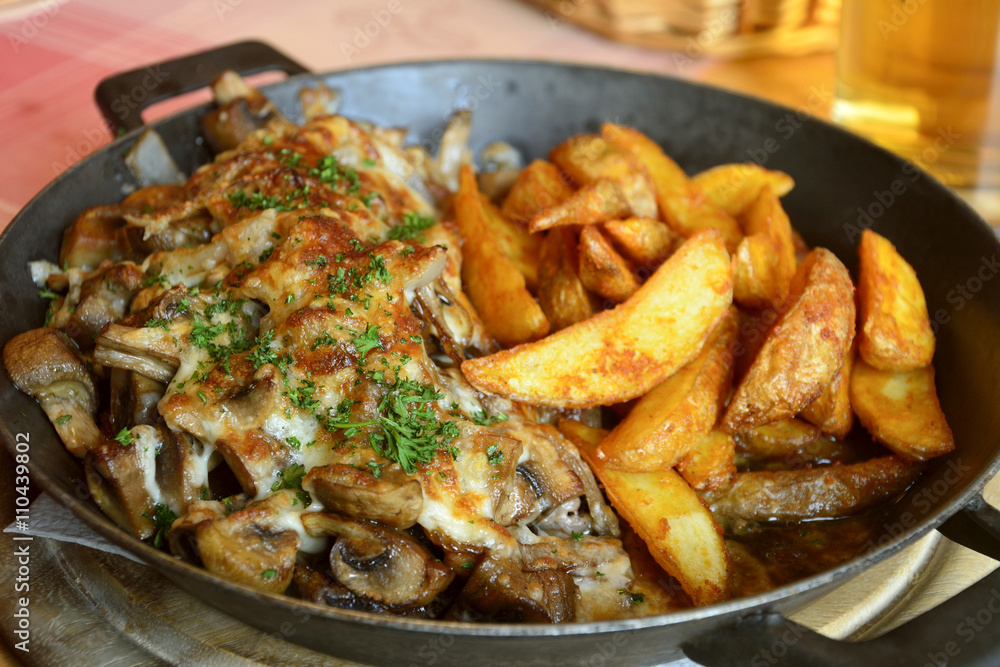 Pork steak with fried mushrooms and onions, gratinated with cheese, served with potato wedges. Pork steak with fried mushrooms and onions, gratinated with cheese, served with potato wedges.