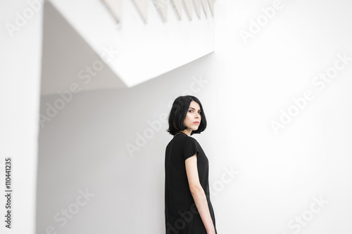 Cuadro en lienzo Calm black-haired woman looking at camera against of white wall