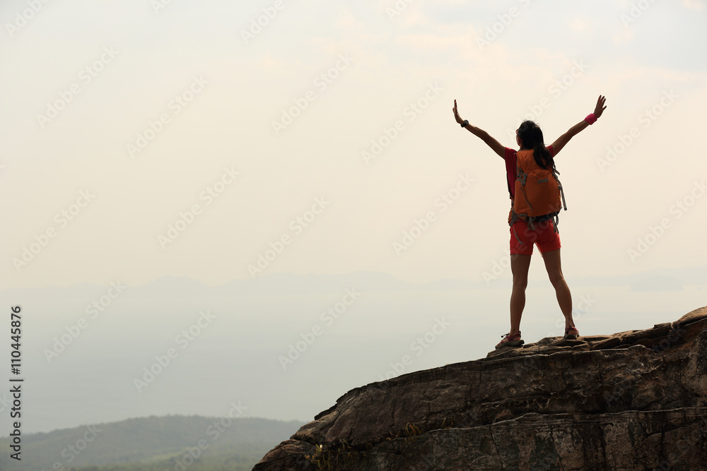  silhouette of young successful woman hiker open arms on mountain peak
