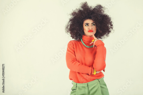 Young woman wearing retro clothes striking a pose in studio. Disco diva