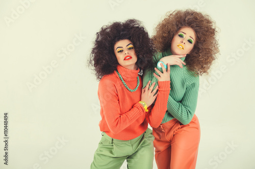 Two funny girls wearing retro clothes in studio. Disco diva over white background