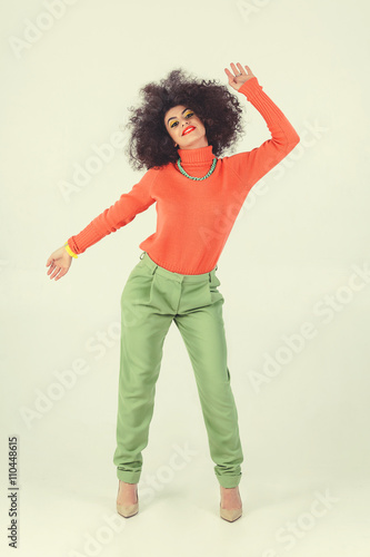 Young woman wearing retro clothes striking a pose in studio. Disco diva