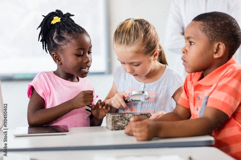 Pupils looking at rock with magnifying glass Pupils looking at rock with magnifying glass