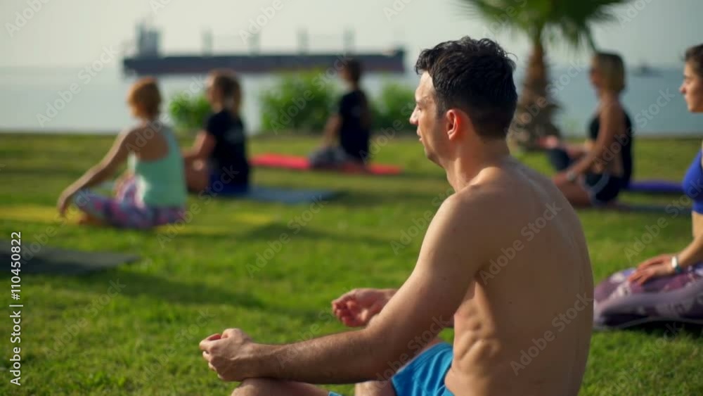 group of people practicing yoga on the grass by the sea slow motion group of people practicing yoga on the grass by the sea slow motion