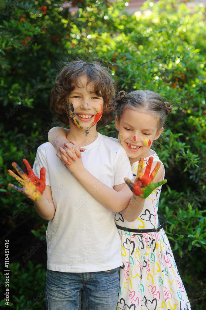 Children embrace, their faces and hands in the paint Children embrace, their faces and hands in the paint