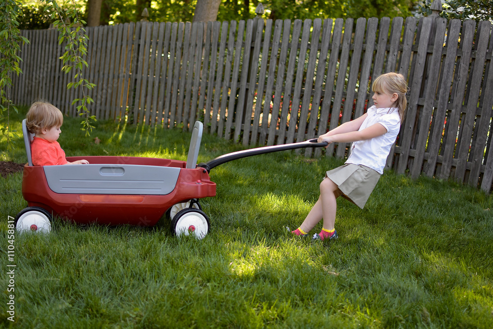 big sister pulling little brother in wagon Stock Photo | Adobe Stock