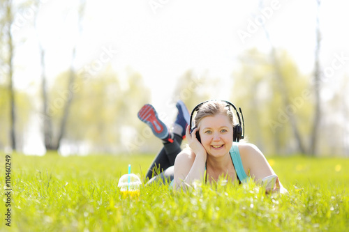 Young woman lying on grass in Park, listening to music on headph photo