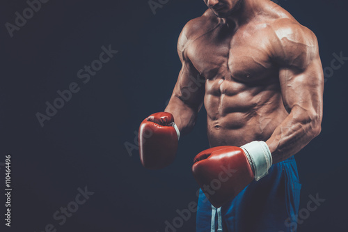 Muscular boxer in studio shooting, on black background. © satyrenko