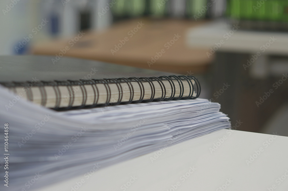 Black notebook and stack of white document Black notebook and stack of white document