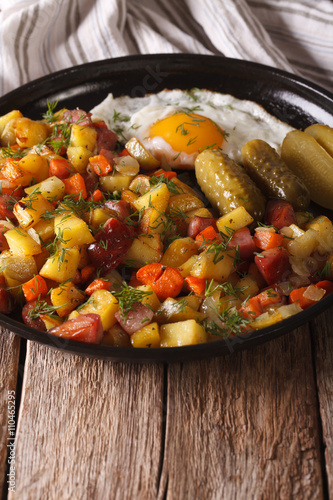 Scandinavian fried potatoes with sausages, eggs and pickled close-up. vertical
 photo