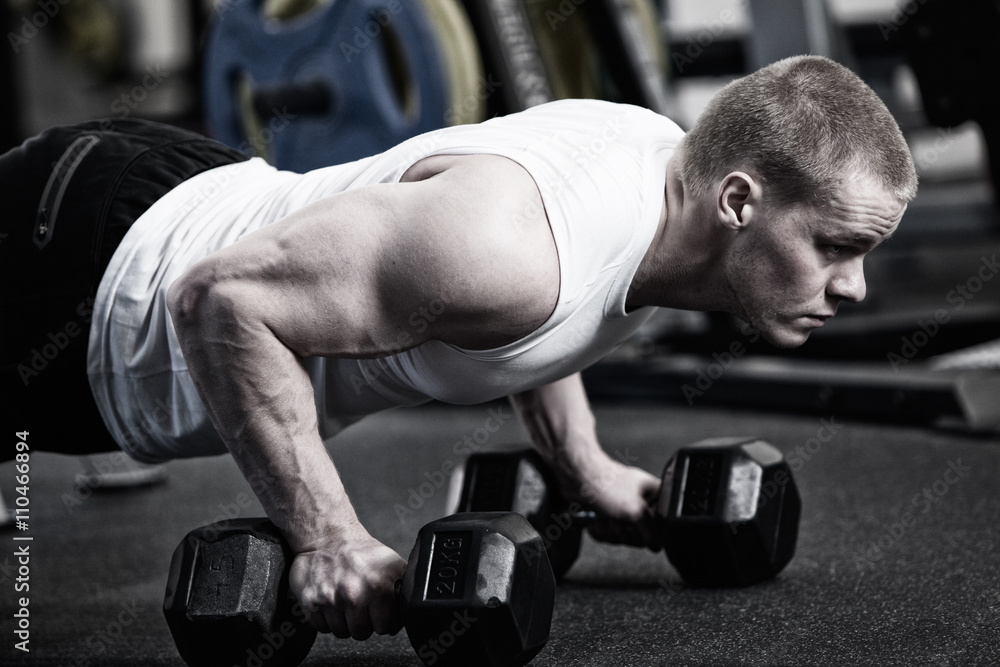 Photo Man doing push up holding dumbbell at the gym Photo Man doing push up holding dumbbell at the gym