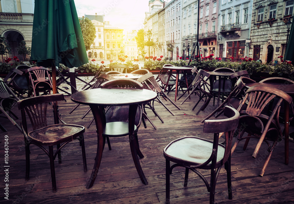 Street cafe terrace with wooden tables and chairs in European ci