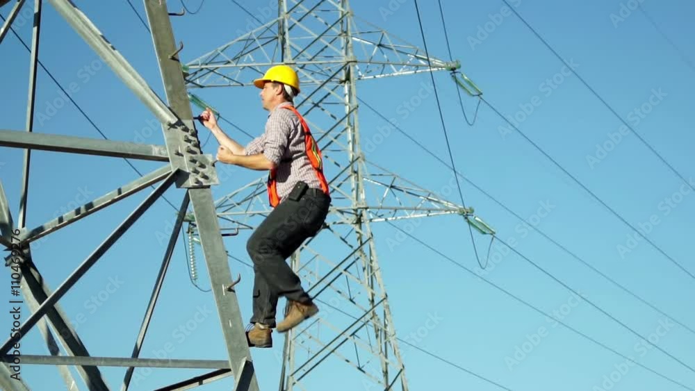 Technician in a safety vest and hard hat climbs high tension electrical tower which is part of the infrastructure for electricity distribution. Technician in a safety vest and hard hat climbs high tension electrical tower which is part of the infrastructure for electricity distribution.