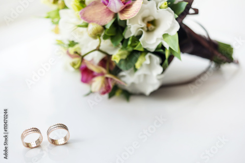 bridal bouquet on white background and two gold rings. Wedding card