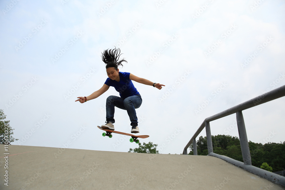 skateboarding woman practice ollie at skatepark ramp