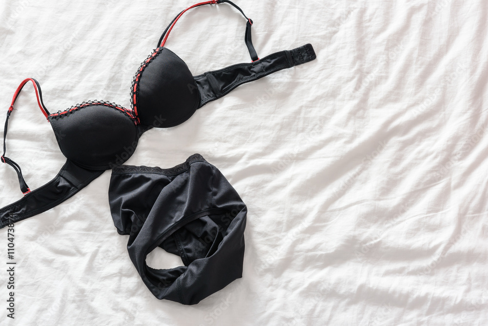 Foto Stock Top view of woman's black bra / lingerie that has been taken off  and put on a messy unmade bed after waking up in the morning and before  going to