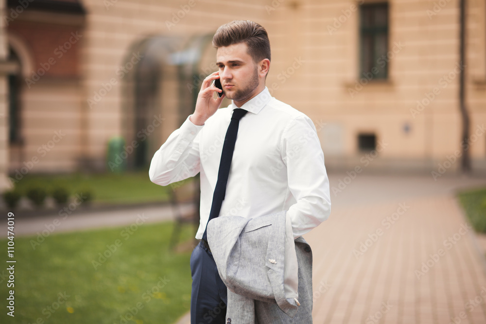 Stylish young businessman talking on the phone outdoors Stylish young businessman talking on the phone outdoors
