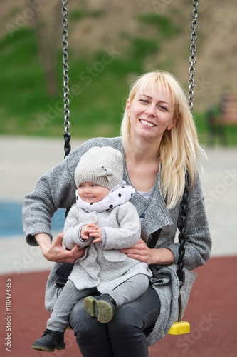 Mother with the little daughter shake on a swing.