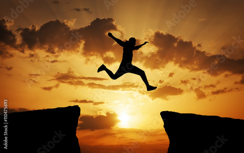 Man jumping across the gap from one rock to cling to the other.