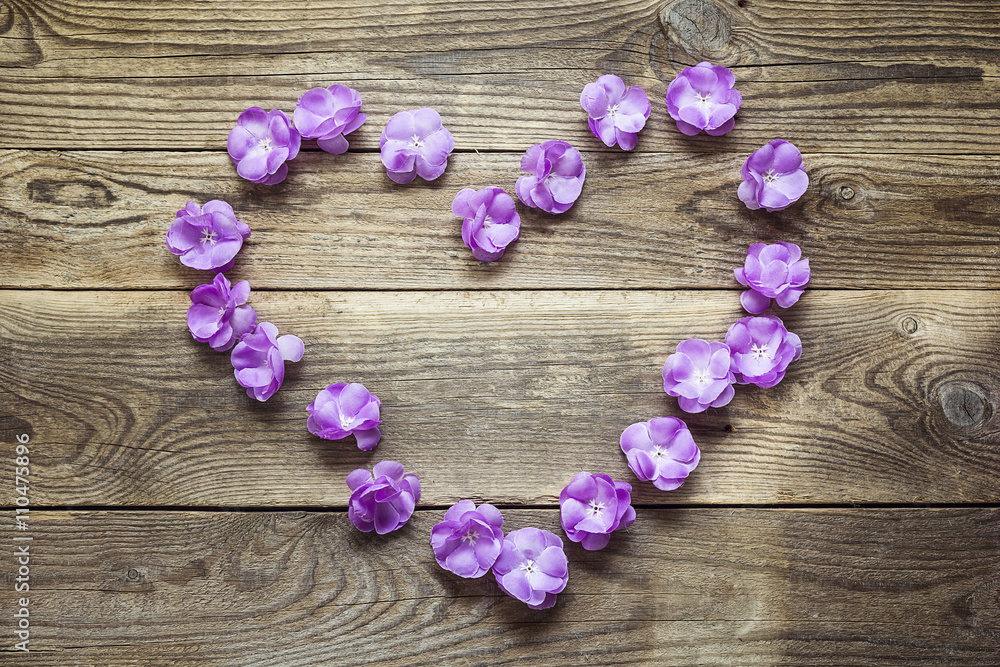 Heart shape made of violet flowers on grunge wooden boards. Plac Heart shape made of violet flowers on grunge wooden boards. Plac