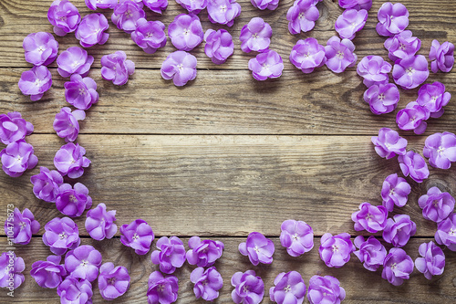 Background with a border of violet flowers on old wooden desks.