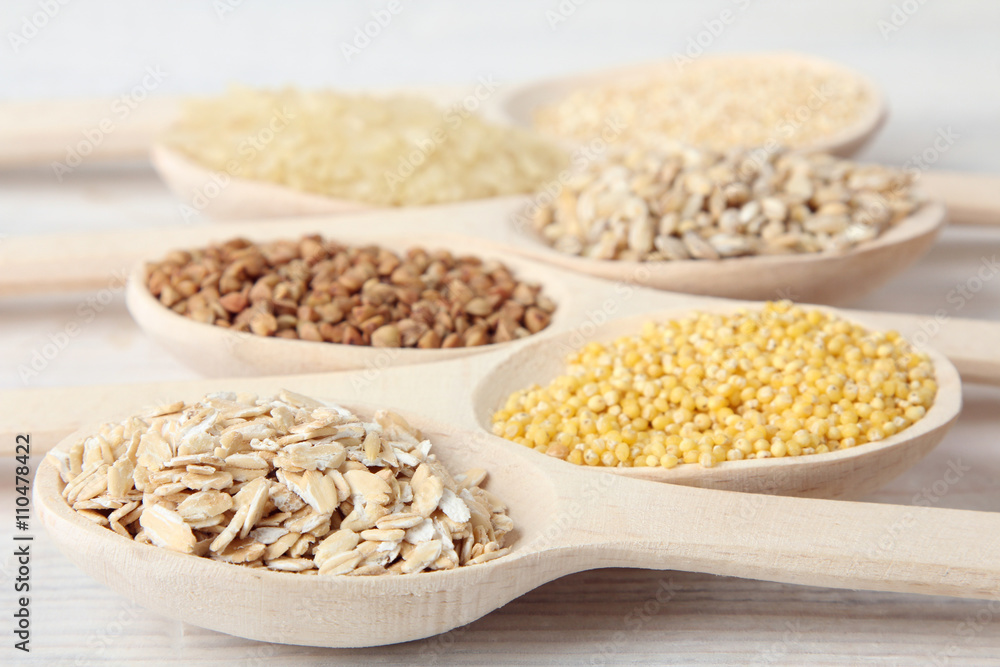 various cereals in wooden spoons on a white wooden table closeup various cereals in wooden spoons on a white wooden table closeup