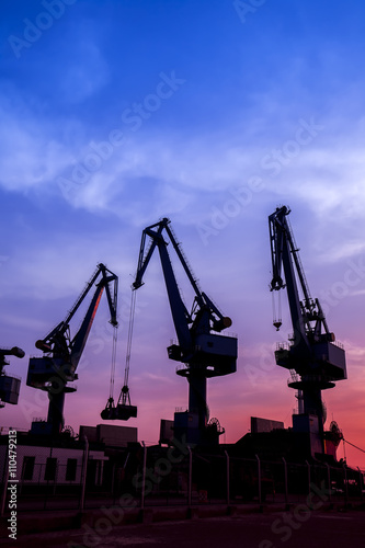 In the evening, the silhouette of port cranes