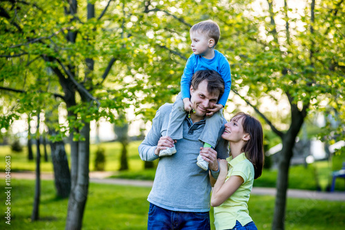Happy young family stands near a flowering tree and smiling