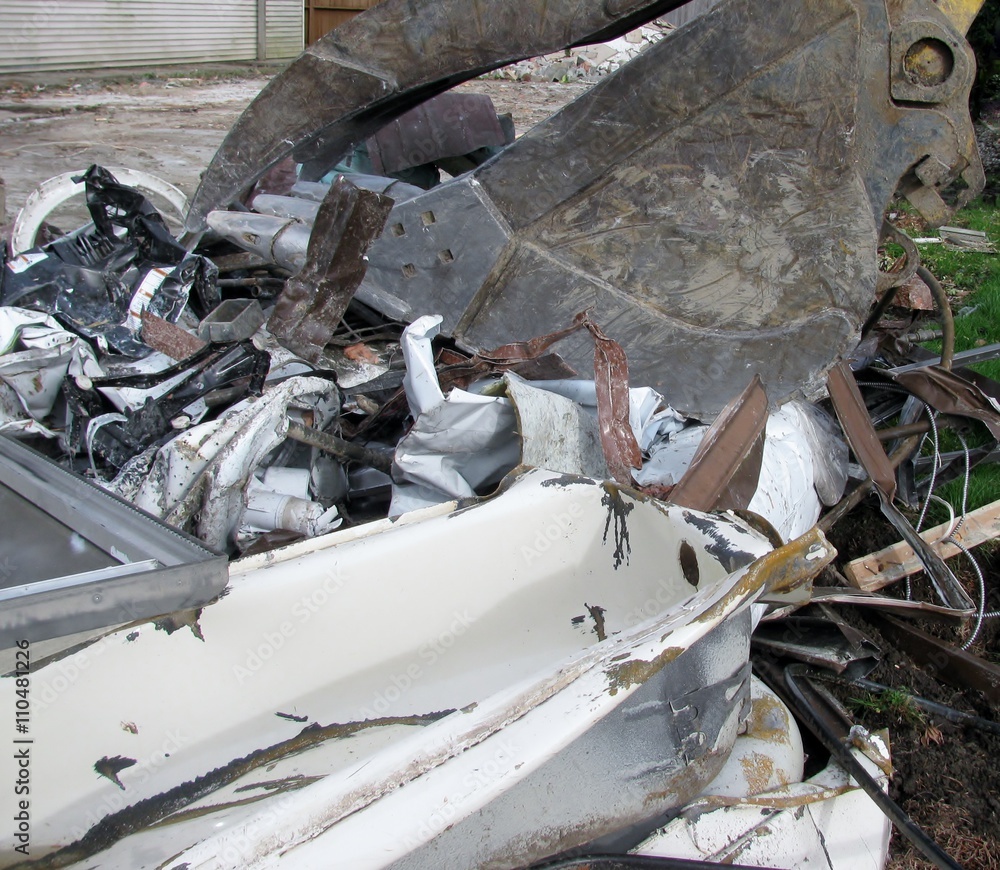 Fototapeta premium Close-up of excavator bucket loading metal parts from house demolition site