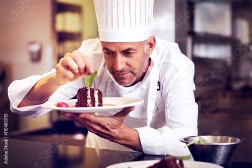 Concentrated male pastry chef decorating dessert in kitchen