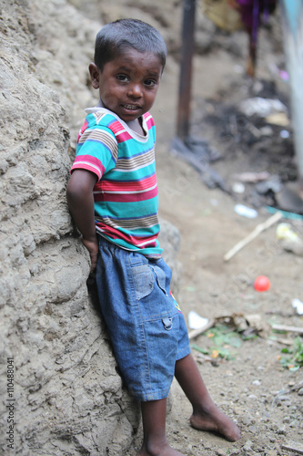 Pune, India - July 16, 2015: A poor Indian boy standing at a con photo