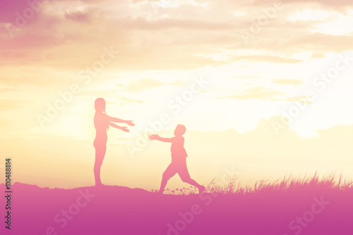 Mother encouraged her son outdoors at sunset, silhouette concept © Johnstocker