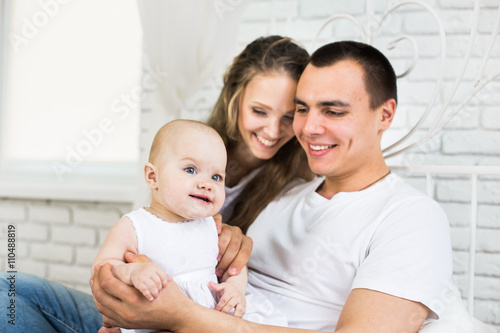 Mother and father with little baby in a bed