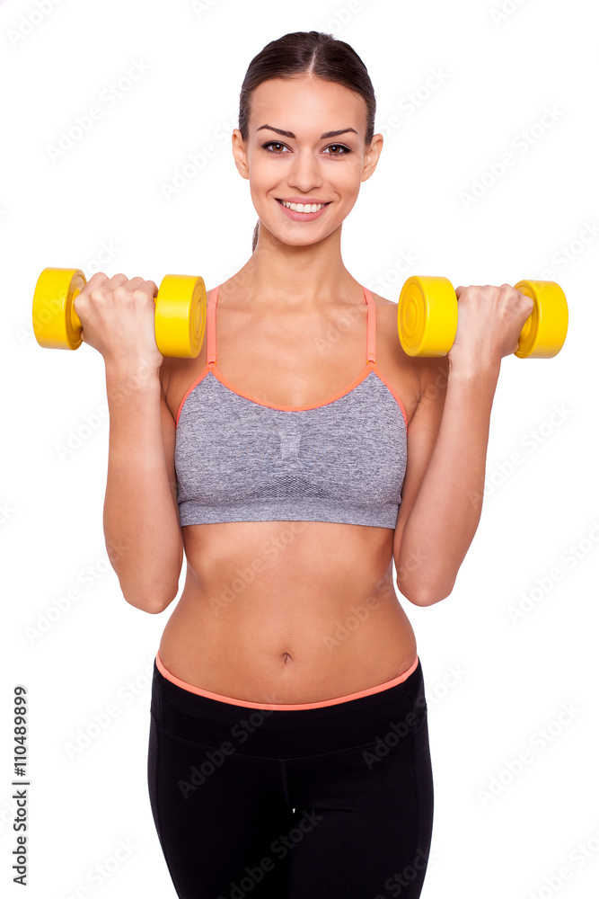 Keeping my body toned. Shot of a beautiful and sporty young woman lifting up weights against white isolated background. Keeping my body toned. Shot of a beautiful and sporty young woman lifting up weights against white isolated background.