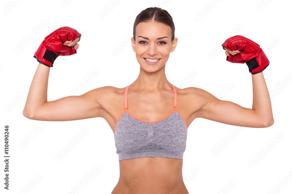 I am a winner! Happy young sporty woman in boxing gloves keeping arms raised while standing against white background